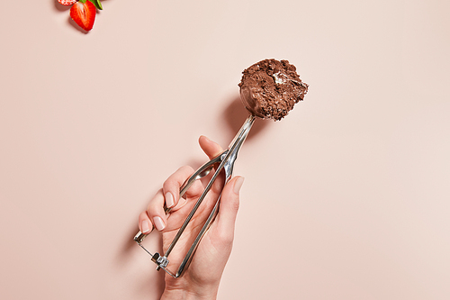 cropped view of woman holding scoop with chocolate ice cream ball near strawberry on pink background
