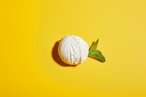 top view of fresh tasty ice cream ball with mint leaves on yellow background