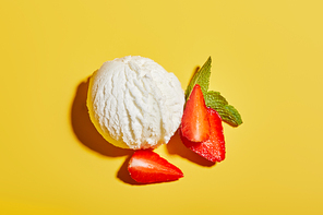 top view of fresh tasty ice cream ball with mint leaves and strawberry on yellow background