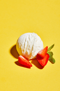 fresh tasty ice cream ball with mint leaves and strawberry on yellow background