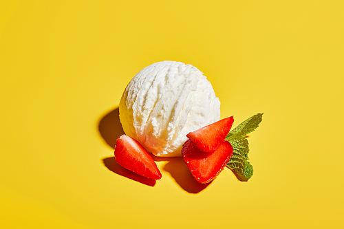 fresh tasty ice cream ball with mint leaves and strawberry on yellow background