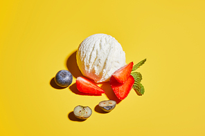 fresh tasty ice cream ball with mint leaves and berries on yellow background