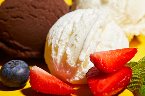 close up view of tasty brown and white ice cream with berries and mint