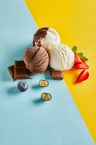 tasty brown and white ice cream with berries, chocolate and mint on blue and yellow background