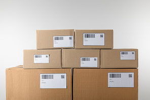 Cardboard packages with barcodes and qr codes on cards isolated on grey