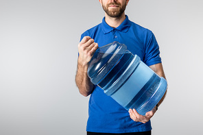 Cropped view of courier holding bottled water isolated on blue