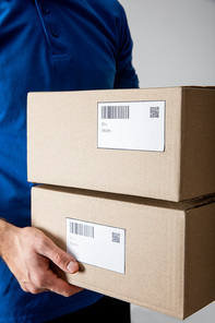 Cropped view of delivery man holding cardboard boxes isolated on grey