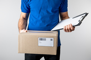 Cropped view of courier holding clipboard and cardboard box isolated on grey