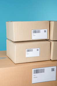 Stacked cardboard packages with barcodes and qr codes isolated on blue