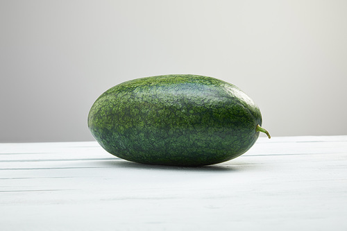 green whole watermelon on white wooden table isolated on grey