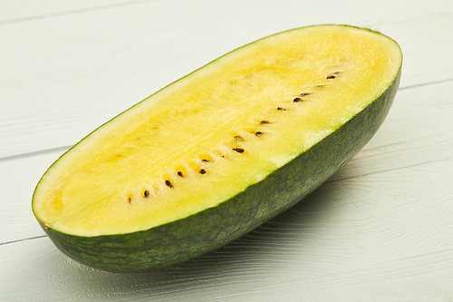 ripe juicy yellow watermelon half on wooden white surface