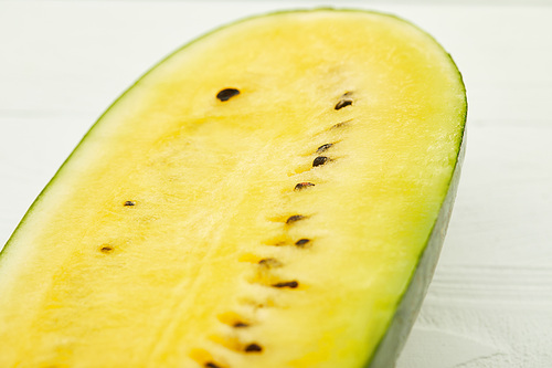 ripe yellow tasty watermelon half with seeds on white wooden table
