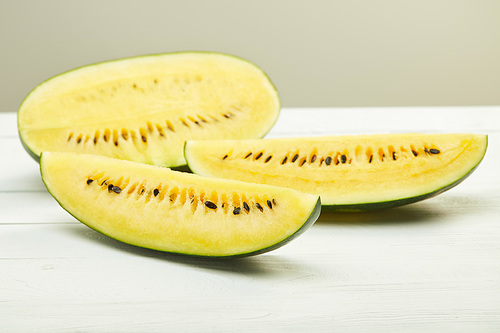 yellow tasty watermelon with seeds on white wooden table isolated on grey