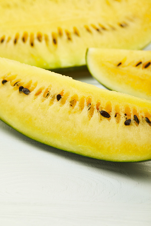 ripe yellow delicious watermelon with seeds on white wooden table