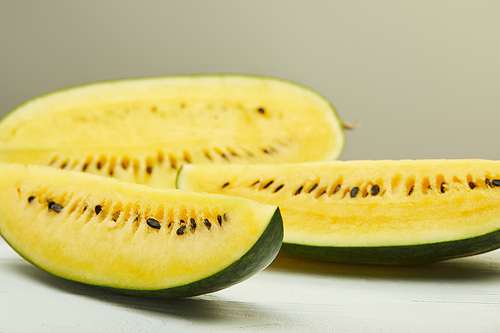 ripe yellow watermelon with seeds on white wooden table isolated on grey