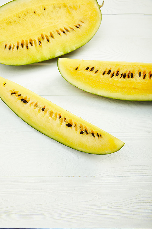 ripe yellow tasty watermelon with seeds on white wooden table with copy space
