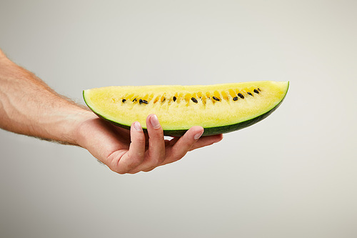cropped view of man holding ripe yellow watermelon slice isolated on grey