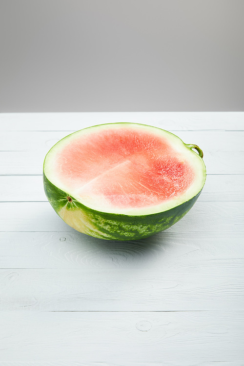 ripe red watermelon half on wooden white table isolated on grey