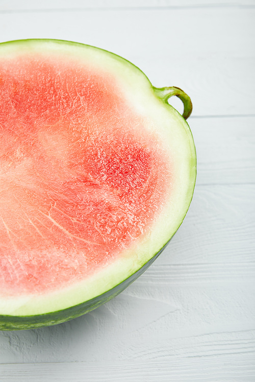 close up view of ripe red watermelon half on wooden white table