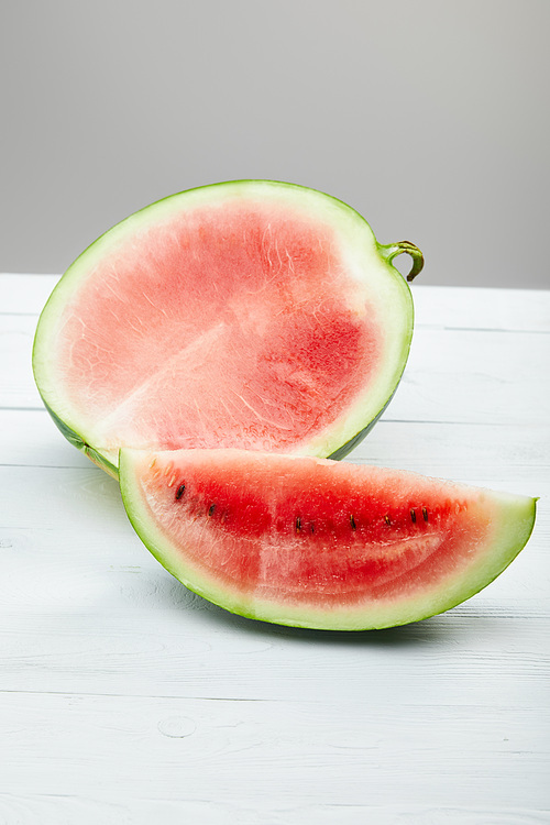 cut delicious red watermelon with seeds on wooden white table isolated on grey