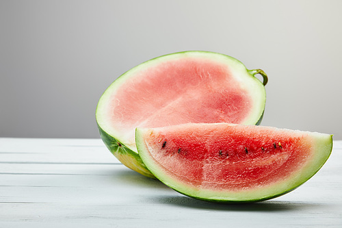 cut ripe red watermelon with seeds on wooden white table isolated on grey