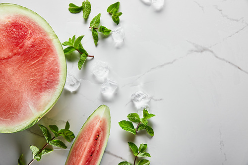 top view of cut delicious red watermelon on marble surface with mint and ice