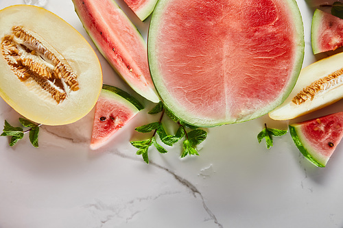 top view of cut delicious exotic red watermelon with  mint on marble surface