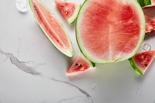 top view of cut delicious exotic watermelon with ice on marble surface