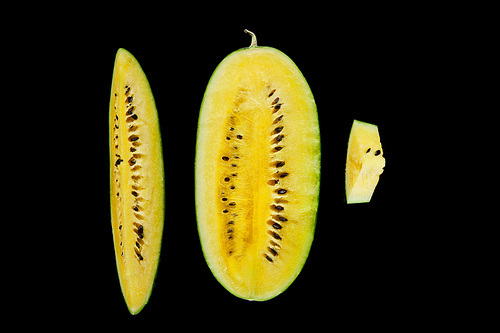top view of delicious ripe yellow cut watermelon with seeds isolated on black