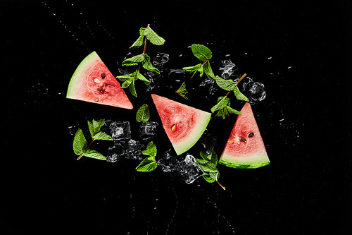 top view of red watermelon slices with mint and ice isolated on black