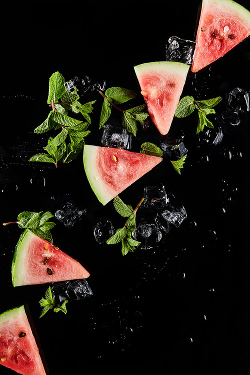 top view of red watermelon slices with mint and ice isolated on black