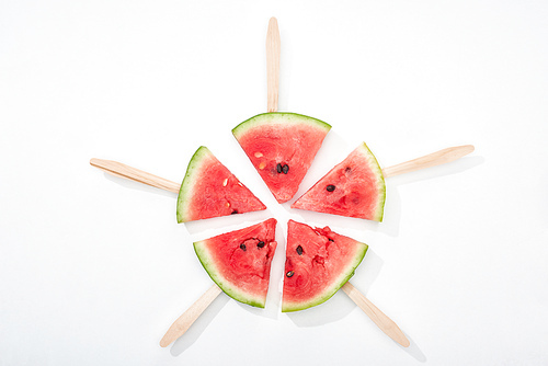 top view of delicious juicy watermelon slices on wooden sticks on white background