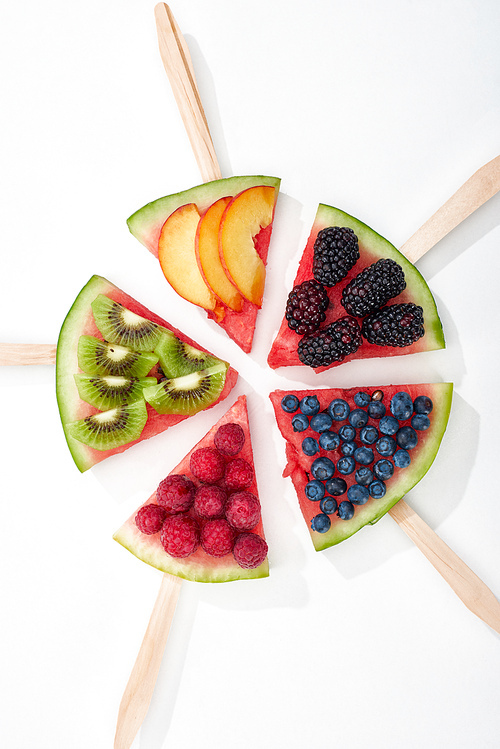 top view of tasty watermelon on sticks with seasonal berries and fruits in circle