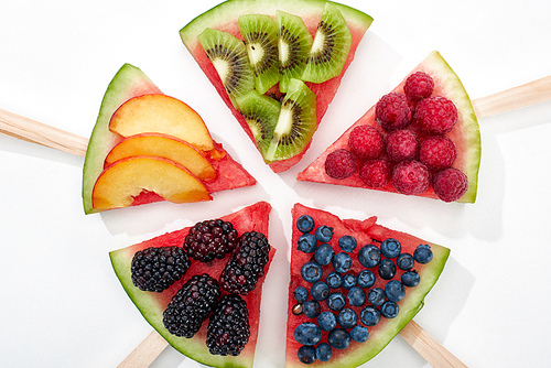 top view of delicious watermelon on sticks with seasonal berries and fruits in circle