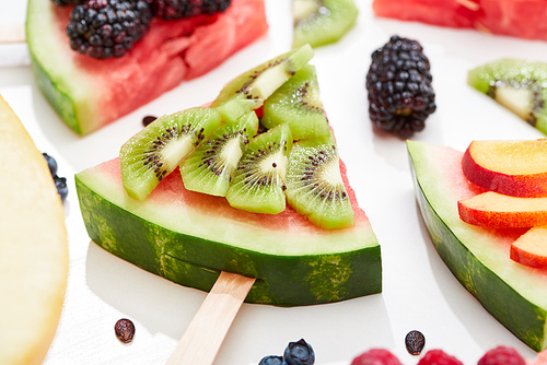 close up view of delicious dessert with watermelon on stick and kiwi on white background