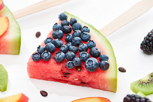 close up view of delicious dessert with watermelon on stick and blueberries on white background
