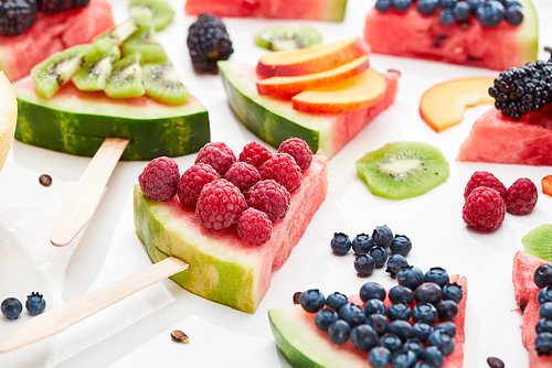 delicious dessert with watermelon on stick and berries on white background