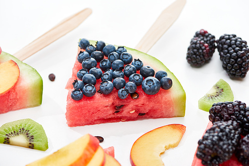 delicious dessert with watermelon on stick and blueberries on white background