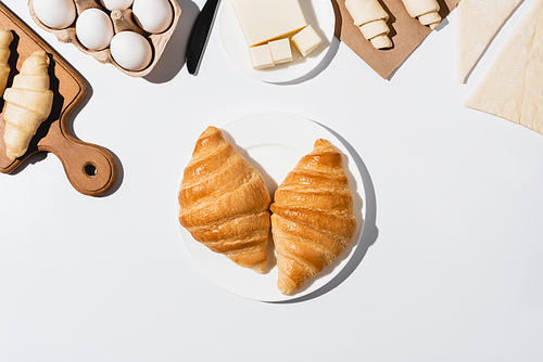 top view of tasty baked croissants on plate on white background