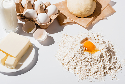 fresh raw dough, flour, milk, butter and eggs on white background