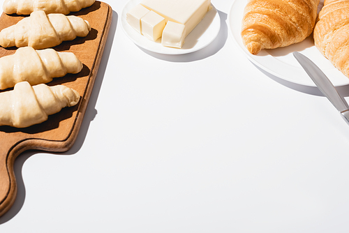 fresh baked and raw croissants with butter on white background