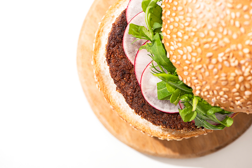 top view of delicious vegan burger with radish and arugula on wooden board on white background