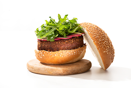 delicious vegan burger with radish and arugula on wooden board on white background