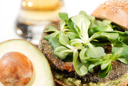 close up view of delicious green vegan burger with microgreens, avocado