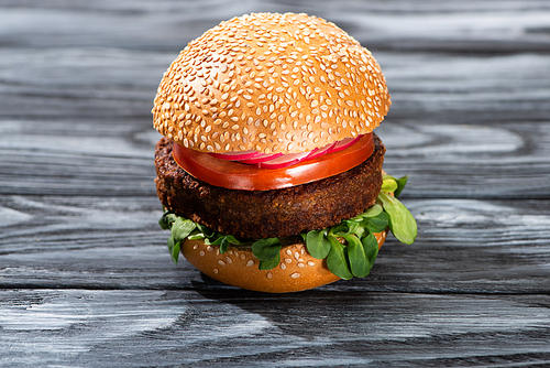 tasty vegan burger with vegetables served on wooden table