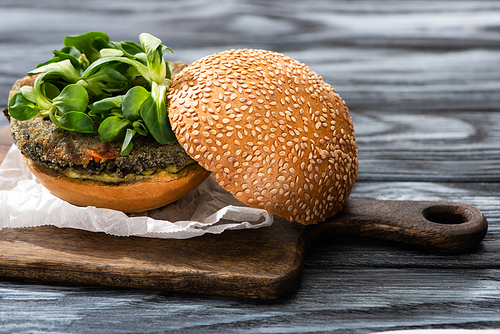 tasty vegan burger with microgreens served on cutting board on wooden table