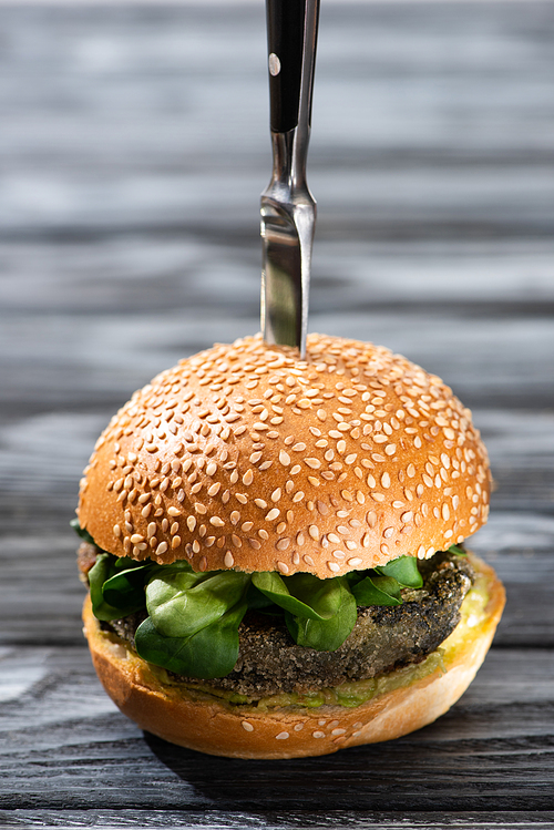 tasty vegan burger with microgreens and knife on wooden table