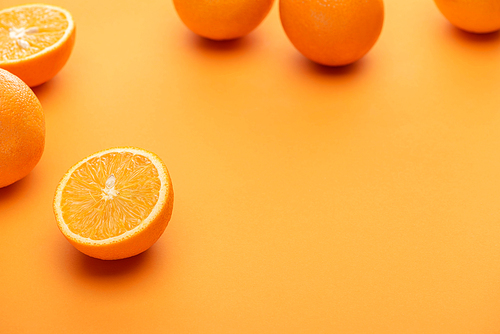 selective focus of ripe juicy whole and cut oranges on colorful background