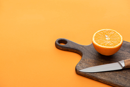 fresh juicy orange half on cutting board with knife on colorful background