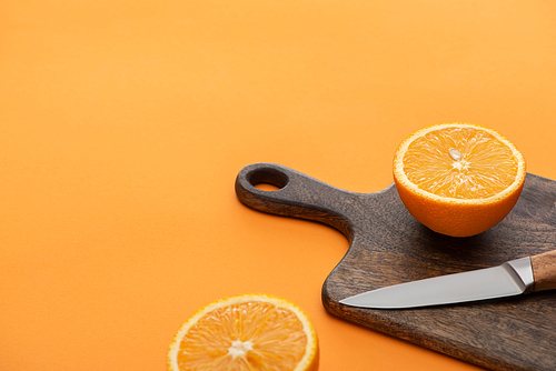 fresh juicy orange halves on cutting board with knife on colorful background